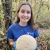 Digital Communications Intern Caitlin May stands in the woods and holds a giant puffball mushroom.