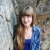 woman from waist up, standing besides a natural wall of rock