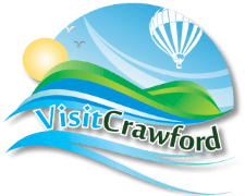 Logo that contains green hills in front of a blue sunny sky, full of birds and a hot air balloon. Text says "Visit Crawford".