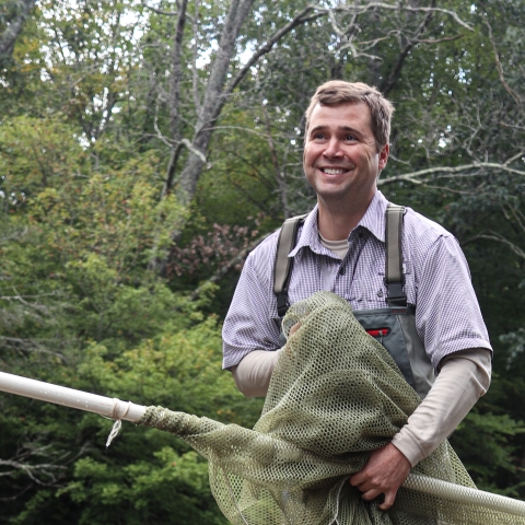 Individual wearing chest waders and holding a net