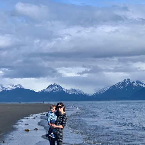 woman standing on a beach with a toddler