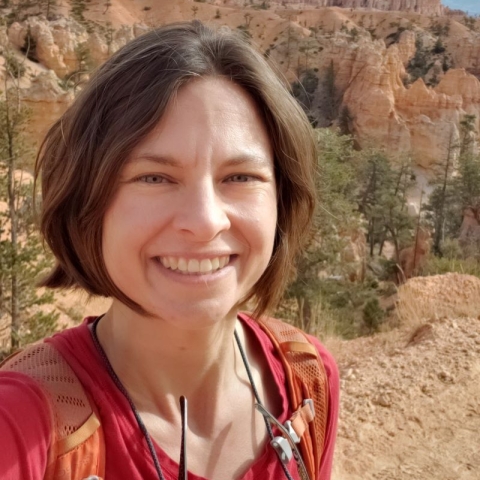 a woman with short dark hair in front of a canyon.