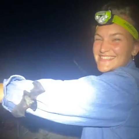 Portrait of Gigi Otten in a cave with a bat flying by