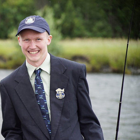 man in a suit with a fishing pole by the water