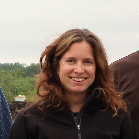 a woman with brown hair and trees in the background