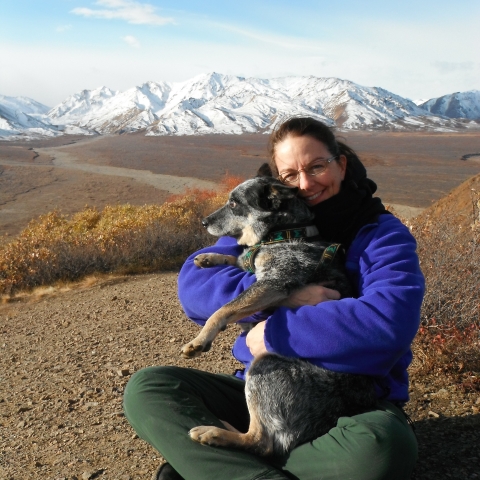 a woman and her dog with mountains in the background