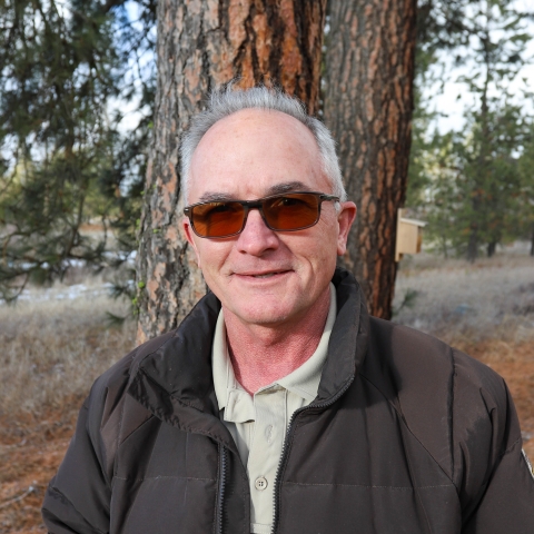 Portrait of man wearing a tan shirt and brown jacket