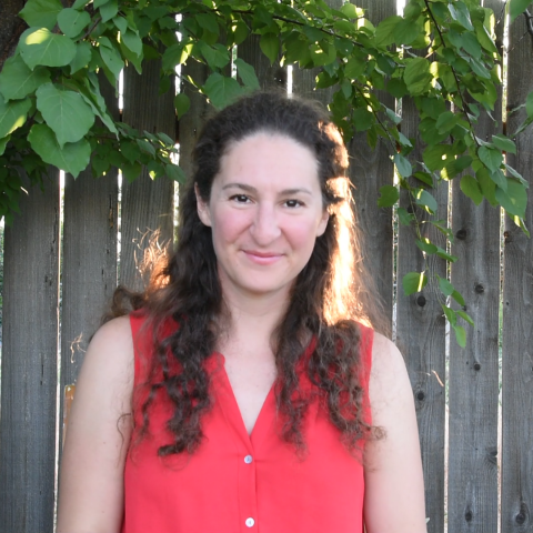 A woman with brown hair in front of a wood fence