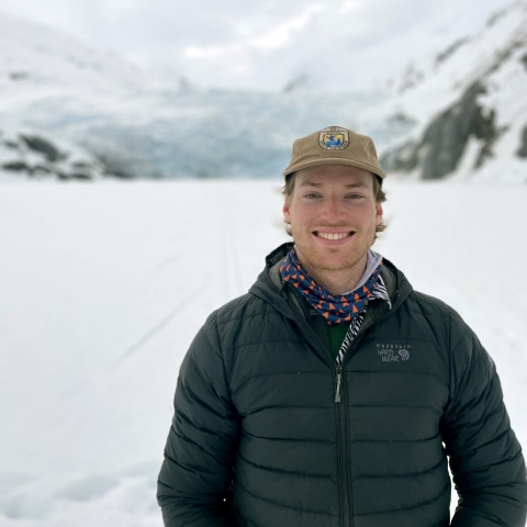 a man standing in snow with mountains behind