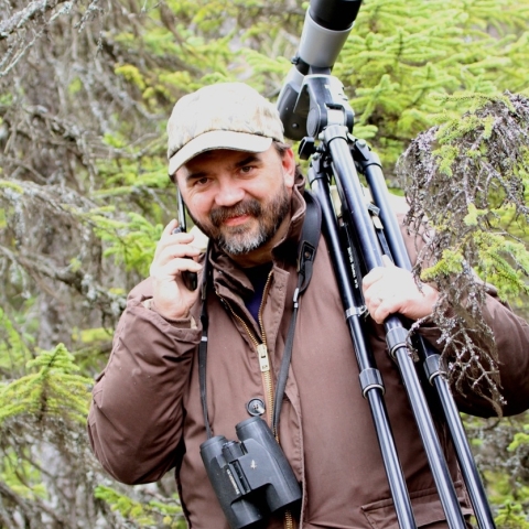 man holding a radio and tripod in the woods