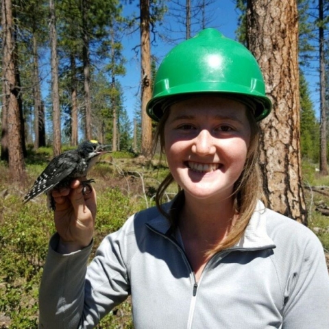 Cameryn Brock holding a black-backed woodpecker