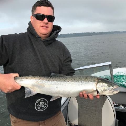 Fish biologist, Ryan Koch, holding a fish while standing on a boat