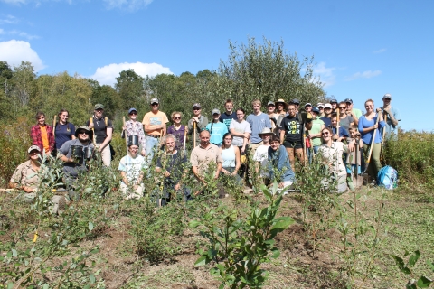 Volunteers at National Public Lands Day event pose for photo holding shovels after a long day work.