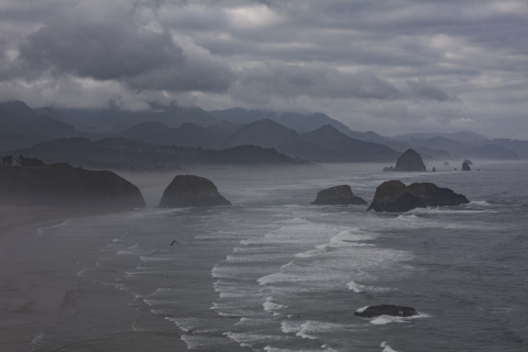 Offshore rocks surrounded by pounding surf lie under dark rainclouds