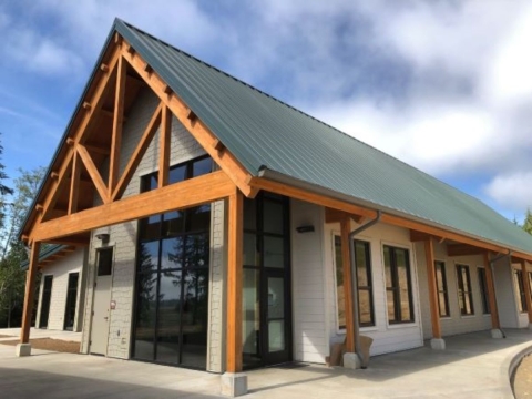 A large building with many windows, wooden rafters and beams and a green roof.