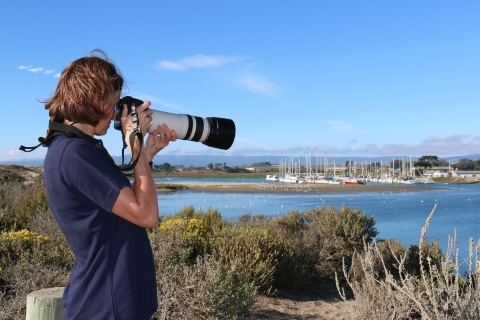 A woman looking out at the water through a camera