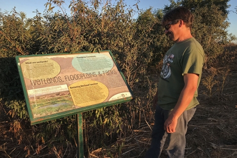 A man standing in front of an educational sign