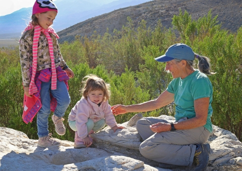 Two small girls climbing on a rock