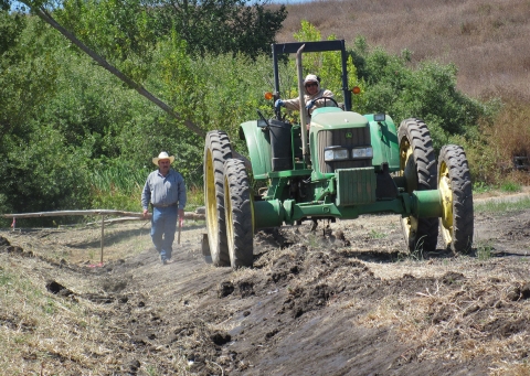 A man walking beside a large green tractor