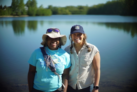 two women standing by a lake