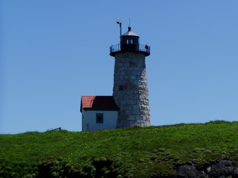 a stone lighthouse with a small structure at its base