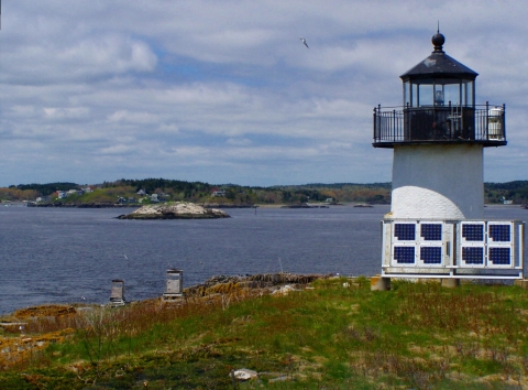 a black and white lighthouse overlooking water and distant land