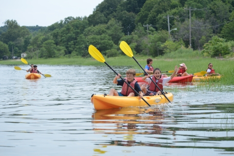 Two young children paddle their kayak through the marsh grasses