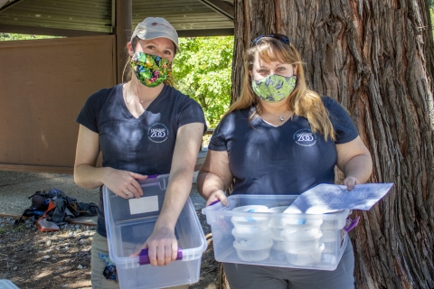 two women holding plastic tubs.