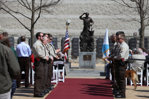 red carpet leading to statue with law enforcement on 2 sides of carper