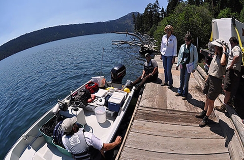 five people on a dock next to a person in a boat