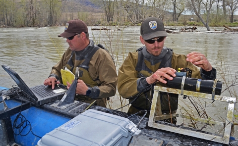 two men standing in a river working with equipment