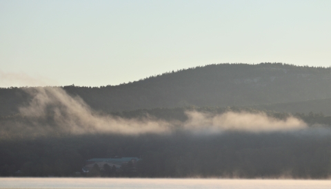 office building on lake's edge with low clouds