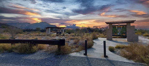 Kiosk and picnic tables against a colorful sunset 