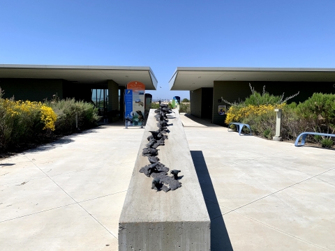 Two buildings with breezeway in between. A block with metal birds is in front of the buildings.