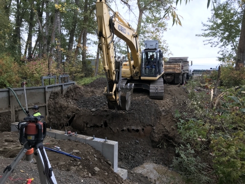 An excavator digs up an old culvert.