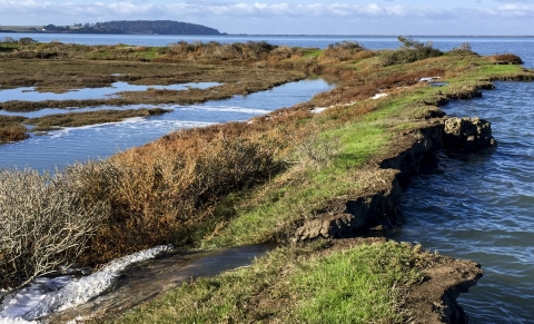 Blue skies with areas of land with water flowing through them.