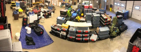 gear organized into plastic containers stored in a warehouse