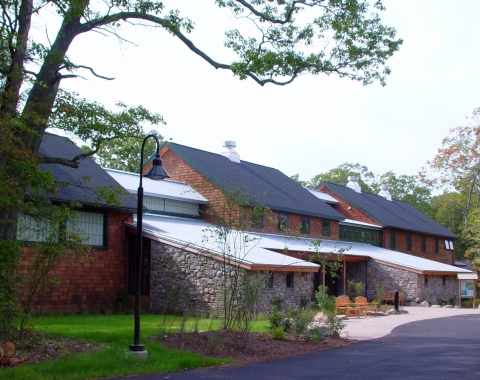 A large, modern brick and stone building in a woodsy setting