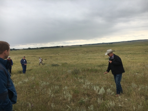 erry Doan, holding a microphone, gestures at the land as he speaks to a small crowd of people on his land