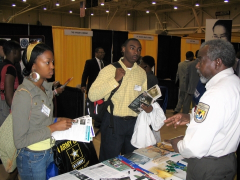 A black man--a Fish and Wildlife Service employee talks with two a male and a female student.