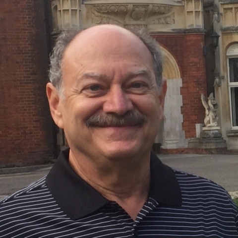 Donald Greenbaum smiles for the camera. A brown, brick building is behind him.