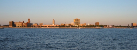 a river flows before a city skyline at sunset