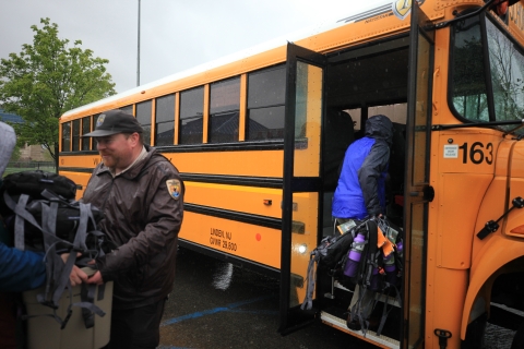 FWS employees carrying outdoor gear onto a bus