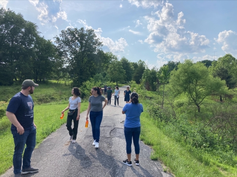 a group of people walking on a national wildlife refuge trail surrounded by forest on a sunny day