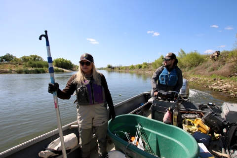 A woman and a man stand on a boat in a river