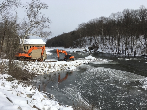 Two orange backhoes beside a river