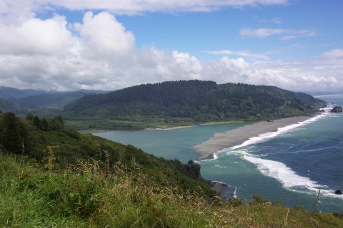 A body of water below hills near the shore with light waves.