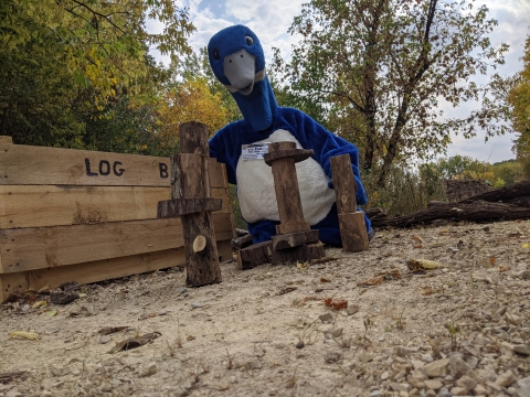 Blue goose mascot playing with logs