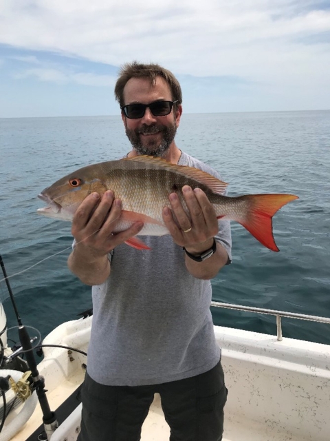 Scott Covington holding a fresh caught fish in his hands while out fishing. 