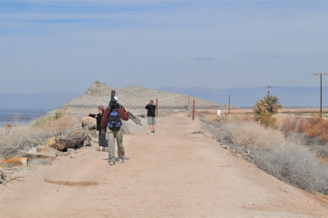 Hikes walking down Rockhill trail with a spotting scope.